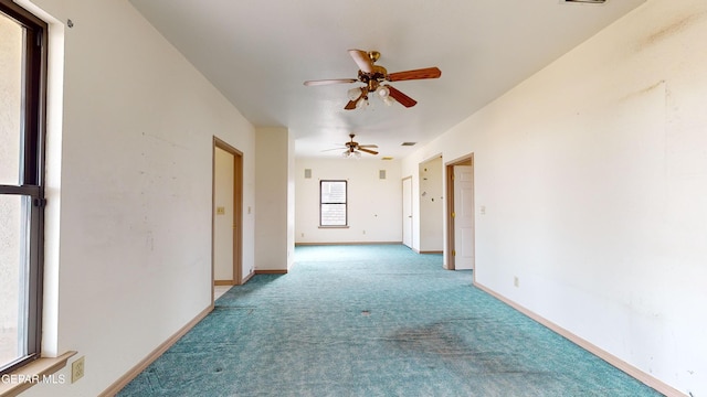 carpeted spare room featuring ceiling fan and a healthy amount of sunlight