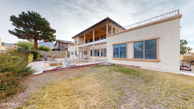 rear view of house with a lawn, a patio area, and a balcony