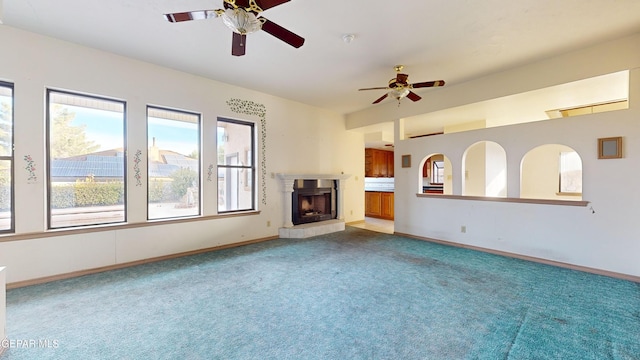 unfurnished living room featuring ceiling fan, a fireplace, and light carpet