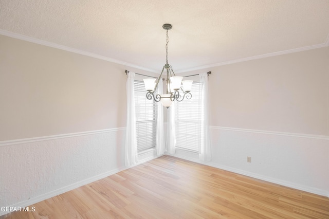 unfurnished dining area with crown molding, light hardwood / wood-style flooring, a textured ceiling, and an inviting chandelier