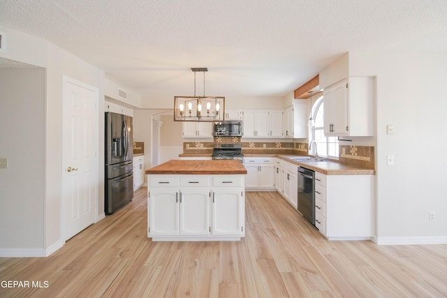 kitchen with wood counters, white cabinets, sink, light hardwood / wood-style flooring, and appliances with stainless steel finishes