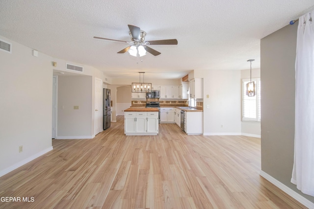 kitchen with white cabinetry, light hardwood / wood-style flooring, butcher block countertops, a textured ceiling, and appliances with stainless steel finishes