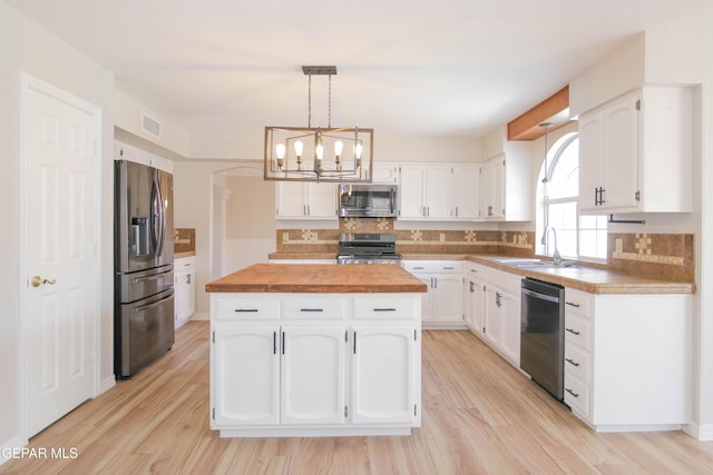 kitchen with white cabinetry, a center island, pendant lighting, appliances with stainless steel finishes, and light wood-type flooring