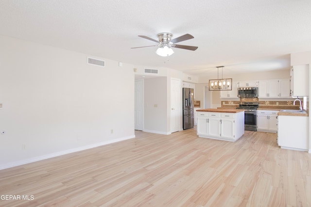 kitchen featuring butcher block counters, white cabinetry, stainless steel appliances, pendant lighting, and light hardwood / wood-style floors