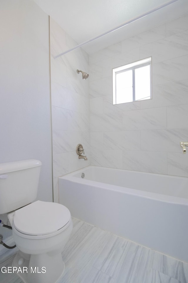 bathroom featuring tiled shower / bath combo and toilet