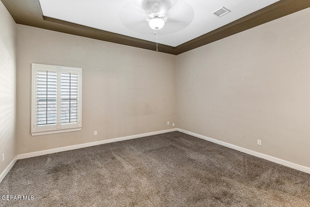 unfurnished room featuring ceiling fan, carpet floors, and a tray ceiling