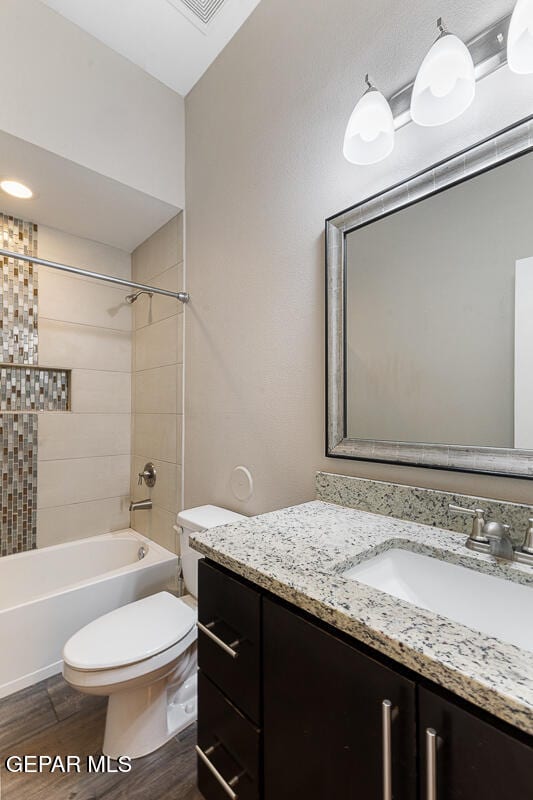 full bathroom with vanity, hardwood / wood-style flooring, toilet, and tiled shower / bath