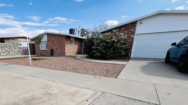 single story home featuring cooling unit and a garage