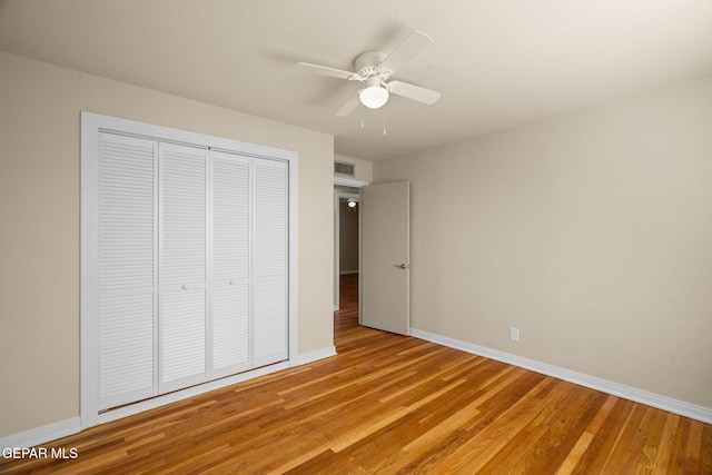 unfurnished bedroom featuring ceiling fan, light wood-type flooring, and a closet