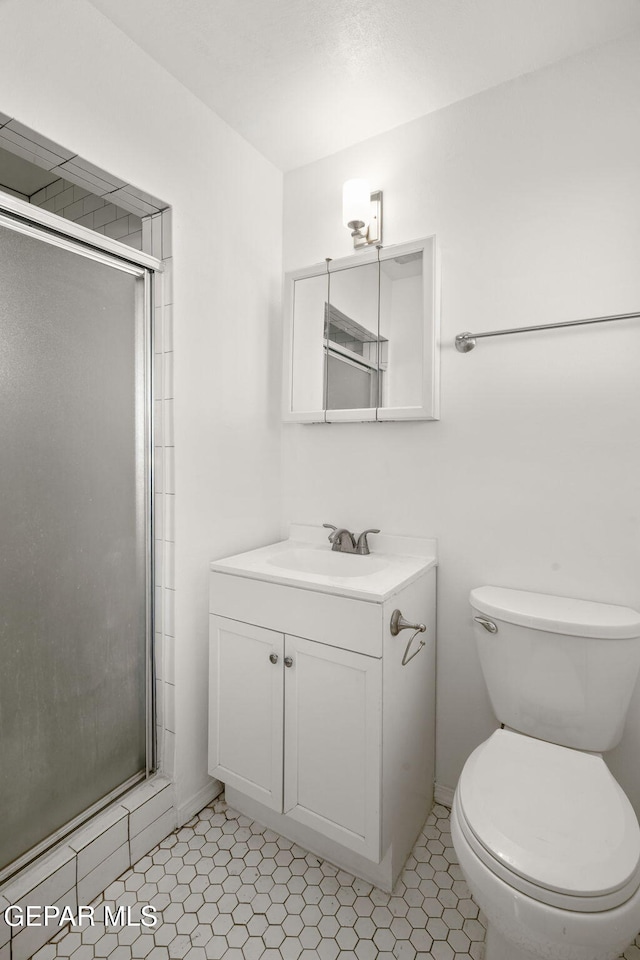 bathroom featuring tile patterned flooring, vanity, toilet, and a shower with door