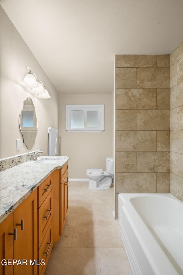 bathroom with tile patterned floors, vanity, toilet, and a tub to relax in