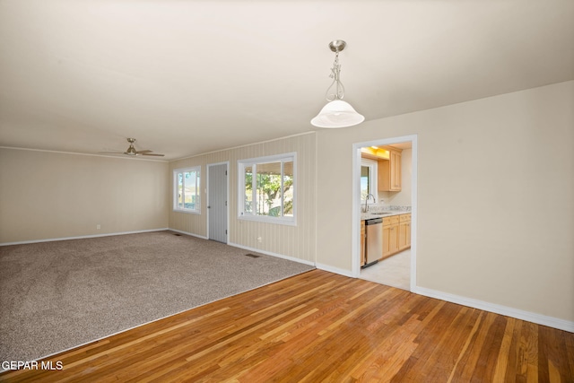 unfurnished living room featuring ceiling fan, sink, and light wood-type flooring