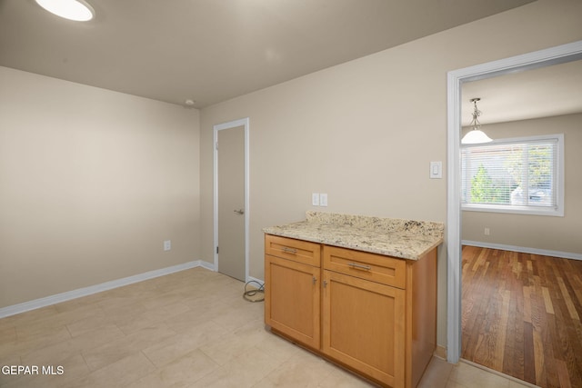 kitchen with light stone countertops, hanging light fixtures, and light wood-type flooring