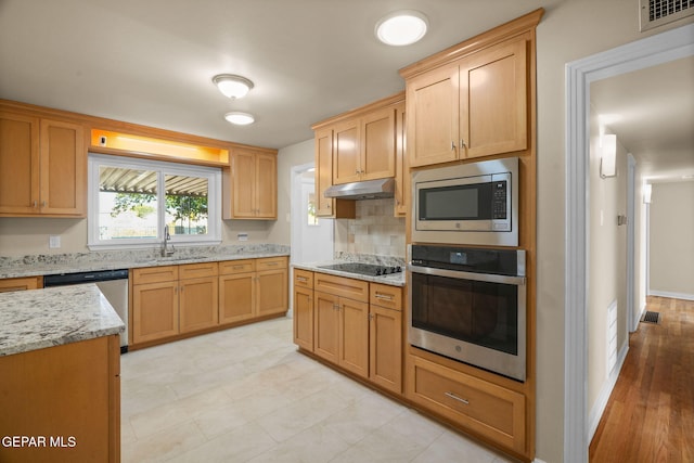 kitchen featuring sink, tasteful backsplash, light stone counters, light hardwood / wood-style floors, and appliances with stainless steel finishes