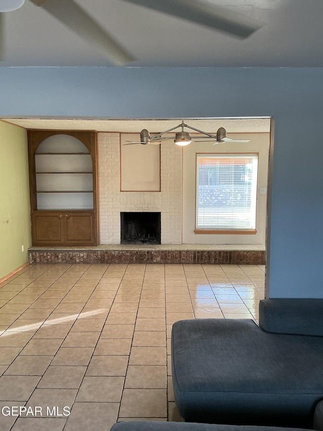 unfurnished living room with ceiling fan, light tile patterned floors, and a fireplace