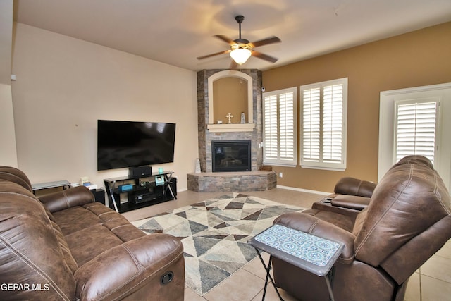 tiled living room with ceiling fan and a fireplace