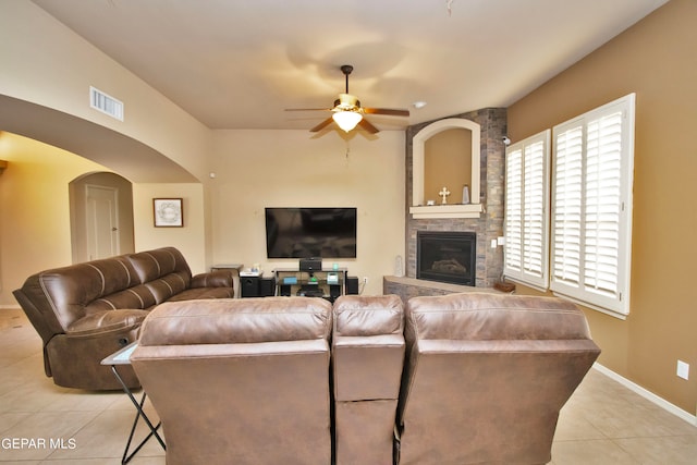 tiled living room with ceiling fan and a fireplace