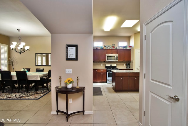 kitchen with a chandelier, light tile patterned flooring, stainless steel appliances, and decorative light fixtures