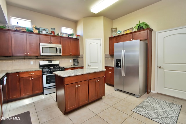 kitchen with light stone countertops, appliances with stainless steel finishes, tasteful backsplash, and light tile patterned floors