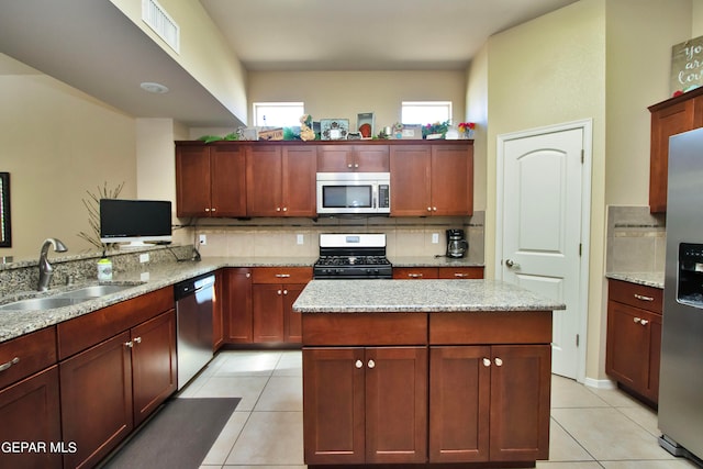 kitchen with light stone countertops, appliances with stainless steel finishes, light tile patterned flooring, and sink