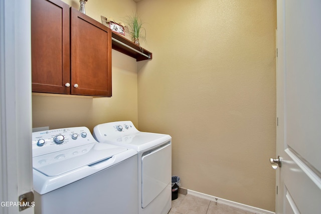 clothes washing area with cabinets, light tile patterned floors, and washer and clothes dryer