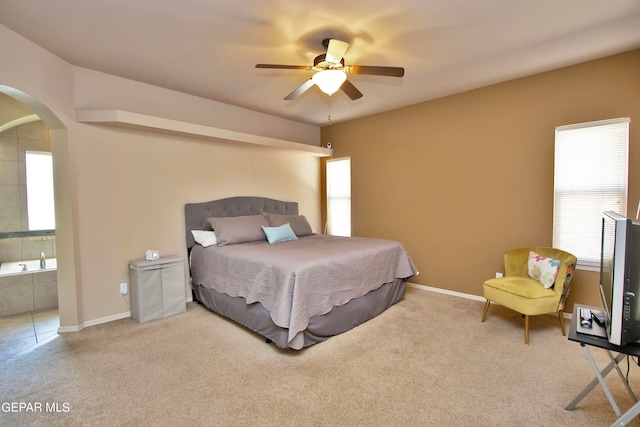 carpeted bedroom with ceiling fan, ensuite bath, and multiple windows