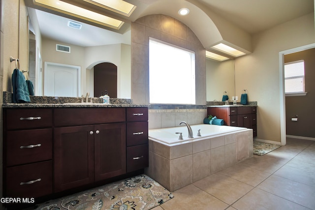 bathroom featuring vanity, a relaxing tiled tub, and tile patterned floors