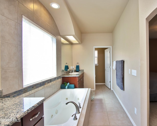 bathroom with tile patterned flooring, plenty of natural light, tiled tub, and vanity