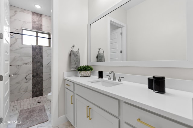 bathroom with vanity, toilet, and tiled shower