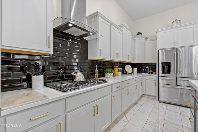 kitchen featuring tasteful backsplash, white cabinets, stainless steel appliances, and wall chimney range hood