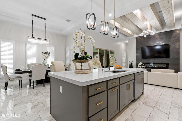 kitchen with a fireplace, pendant lighting, a center island with sink, and sink