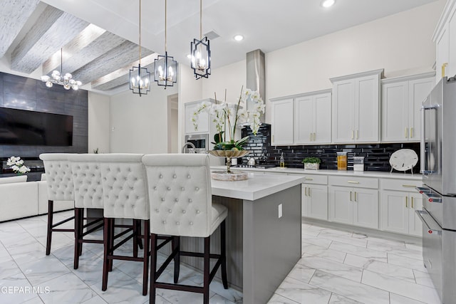 kitchen featuring a center island, white cabinets, hanging light fixtures, tasteful backsplash, and a breakfast bar area