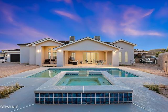 back house at dusk with a pool with hot tub and a patio area