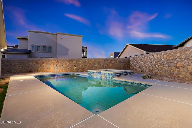 pool at dusk with a patio area and an in ground hot tub