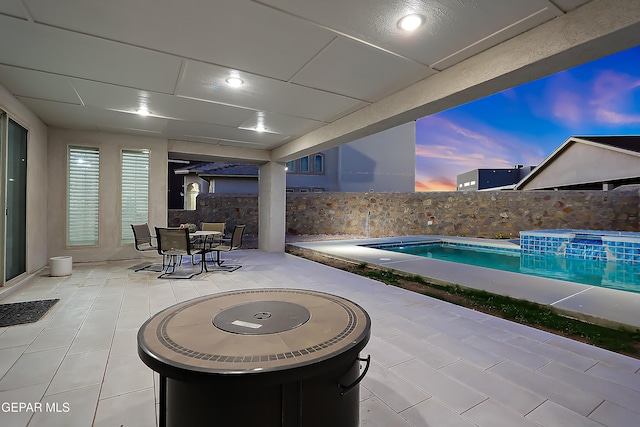 patio terrace at dusk with a fenced in pool