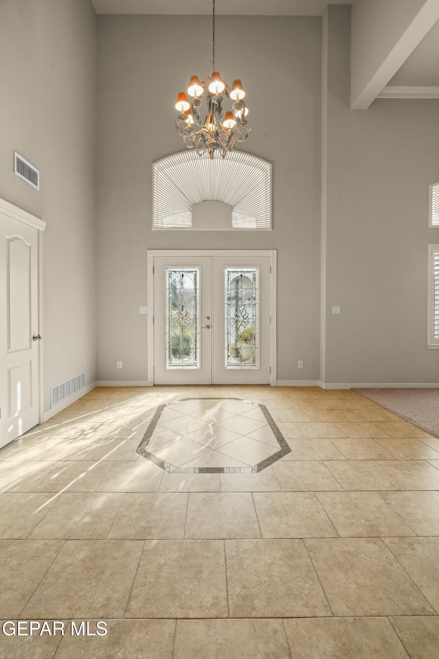 tiled foyer with a high ceiling, an inviting chandelier, and french doors