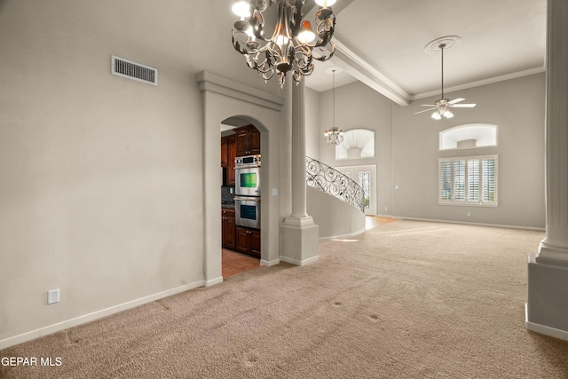 empty room featuring decorative columns, a towering ceiling, ceiling fan with notable chandelier, crown molding, and light colored carpet