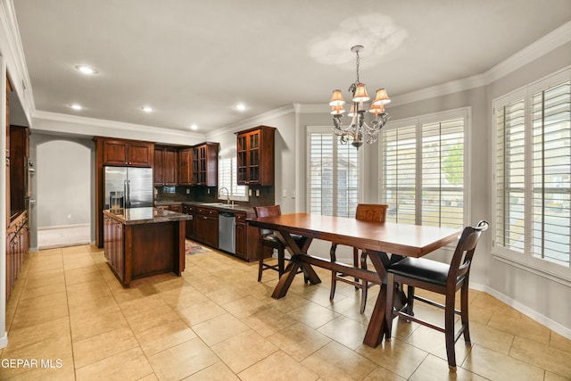 kitchen featuring sink, pendant lighting, dark stone counters, a kitchen island, and stainless steel appliances