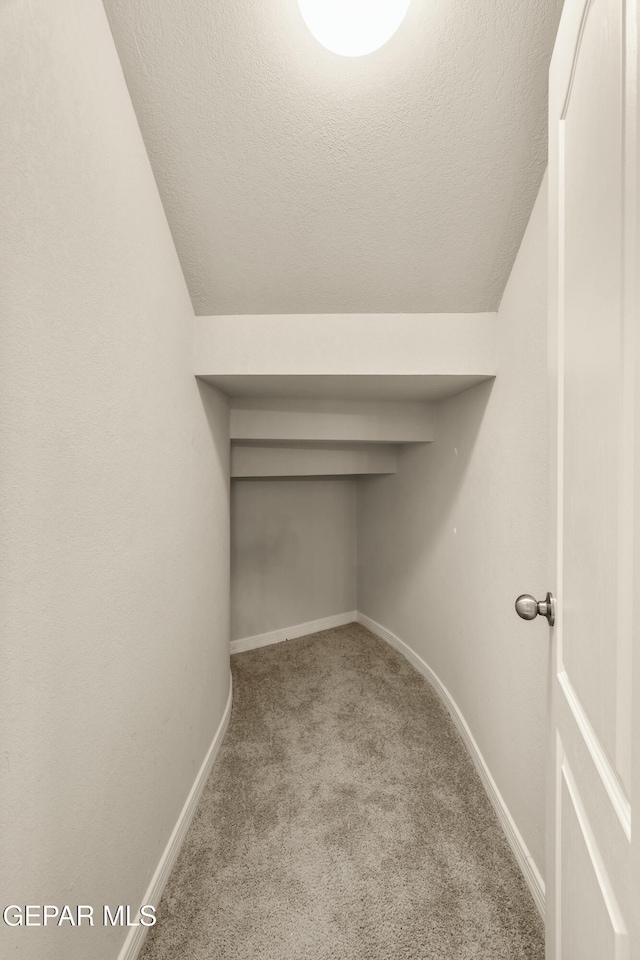 walk in closet featuring light colored carpet and lofted ceiling