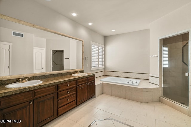 bathroom featuring plus walk in shower, vanity, and tile patterned flooring