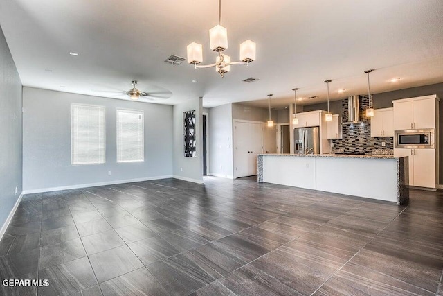 unfurnished living room featuring visible vents, baseboards, and ceiling fan with notable chandelier