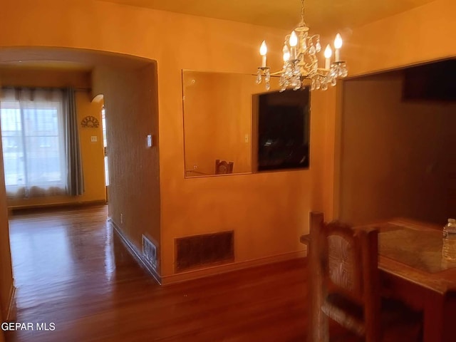 dining room with an inviting chandelier and dark wood-type flooring