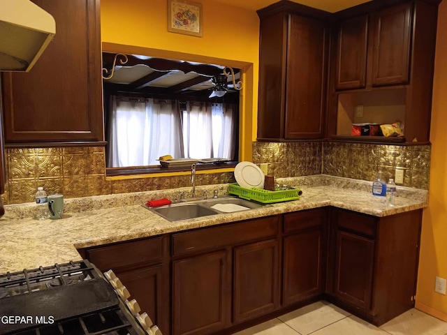 kitchen with decorative backsplash, sink, light tile patterned floors, and light stone countertops