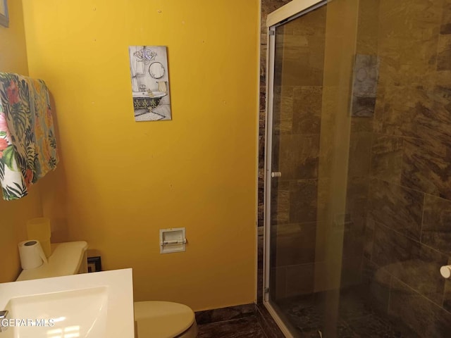 bathroom featuring a shower with shower door and toilet