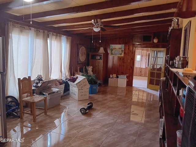 living area with beam ceiling, tile patterned floors, ceiling fan, and wooden walls