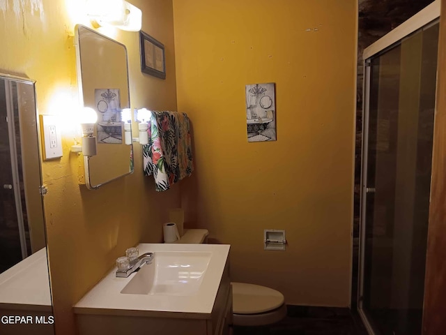 bathroom featuring vanity, toilet, and a shower with door