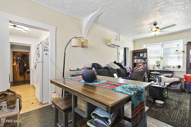 dining room featuring a wall unit AC, ceiling fan, and a textured ceiling