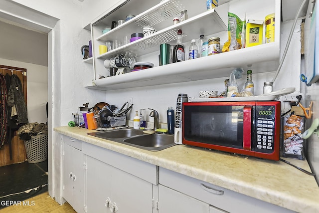 interior space with white cabinets, sink, and light parquet flooring