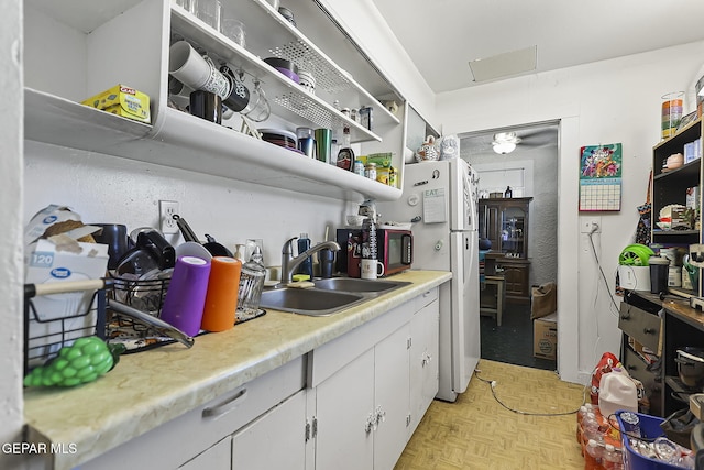 kitchen featuring white cabinetry, sink, and light parquet floors