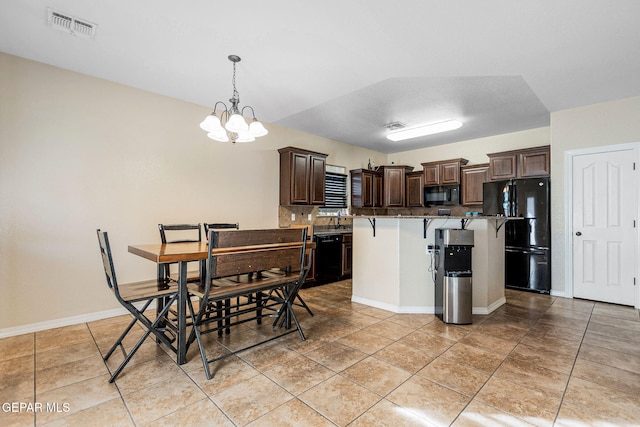 kitchen featuring an inviting chandelier, black appliances, decorative light fixtures, a kitchen island, and a breakfast bar area